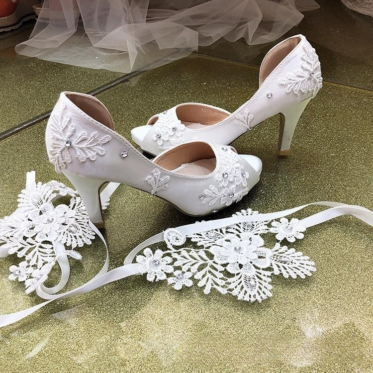 Nuevos zapatos de boda con tacón de aguja y cinta de flores y encaje blanco